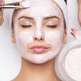 visage avec pinceau appliquant la crème.