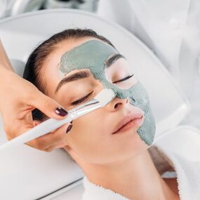 femme se faisant appliquer un masque d'argile.