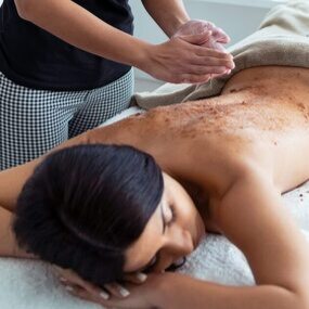 Personne exfoliant le dos d'une femme.